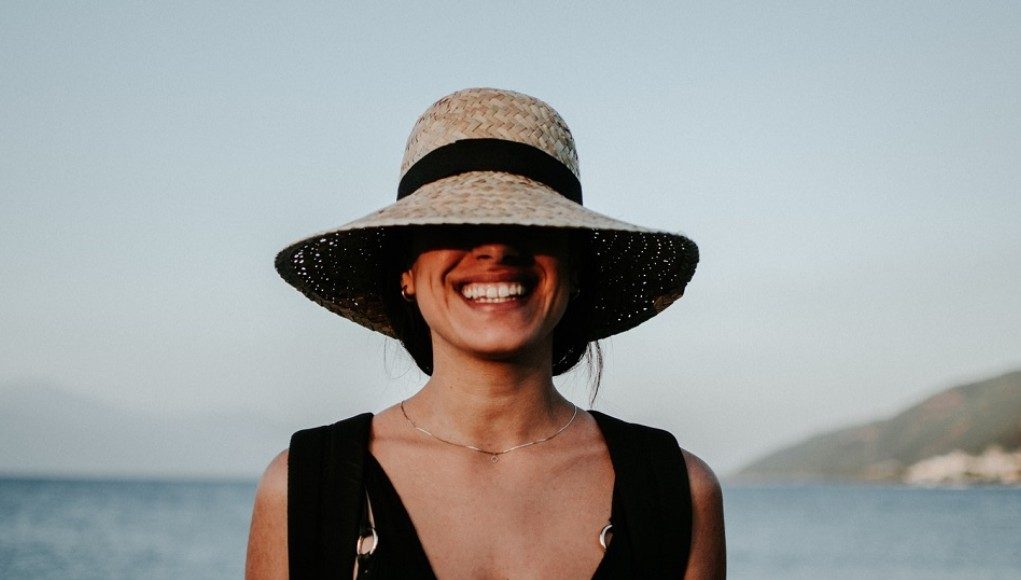 Lachende vrouw op strand met hoed