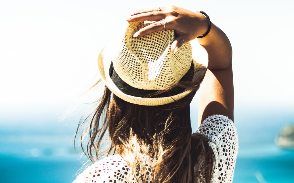 Vrouw met hoed aan zee