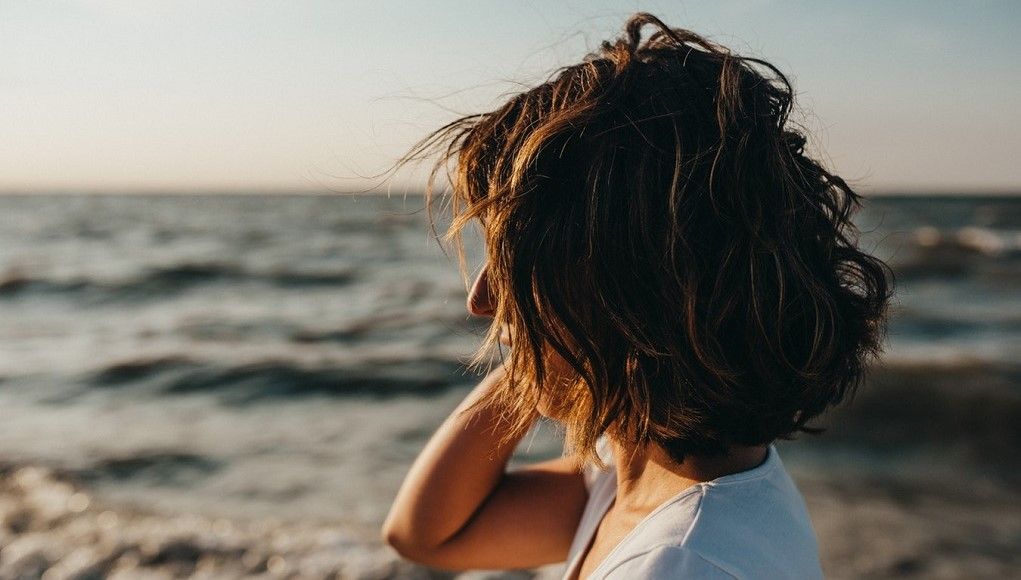 Vrouw kijkt voor zich uit op het strand
