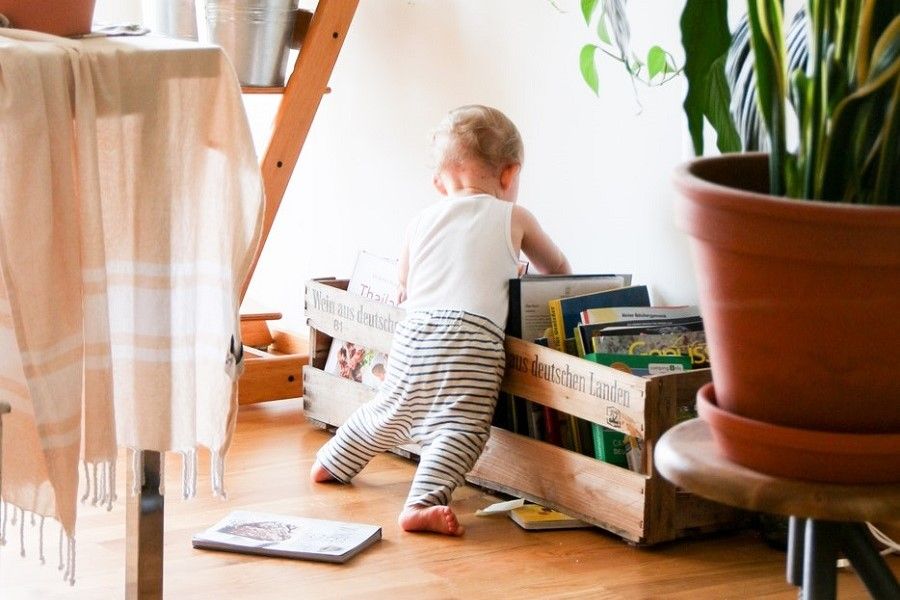 Tips om je kinderen bezig te houden met slecht weer: kind zoekt voorleesboekje uit