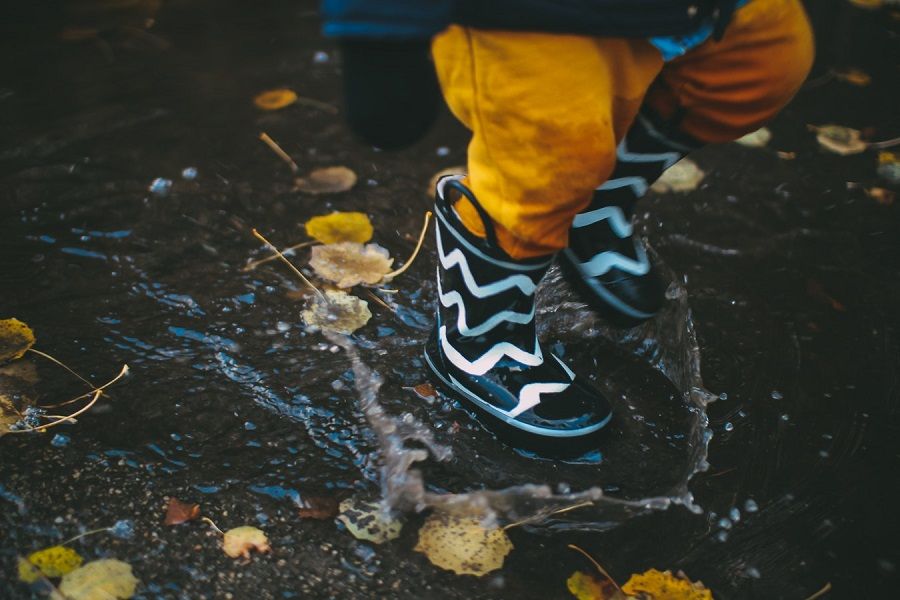 Tips om je kinderen bezig te houden met slecht weer: kind springt in een plas