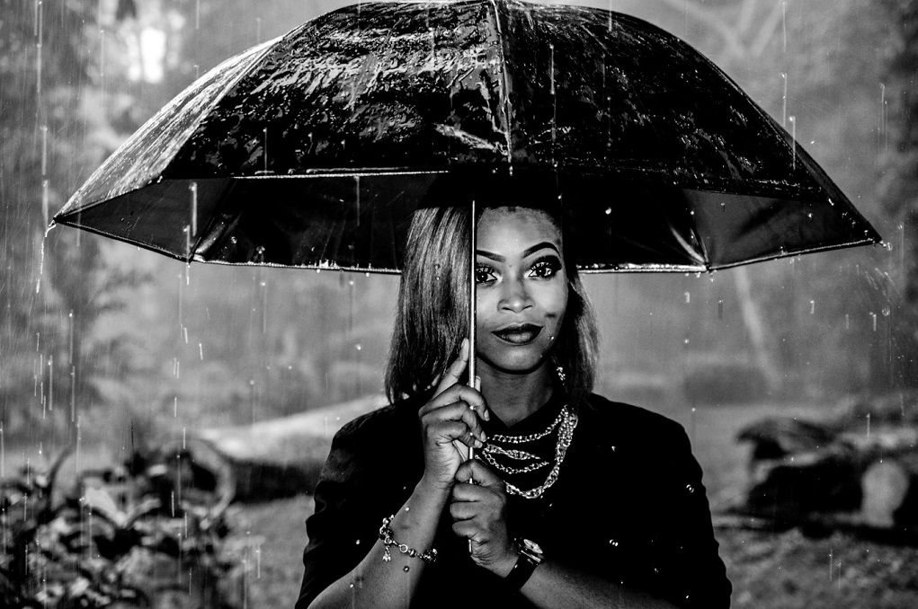 Tips om je kinderen bezig te houden met slecht weer: vrouw onder paraplu in de regen