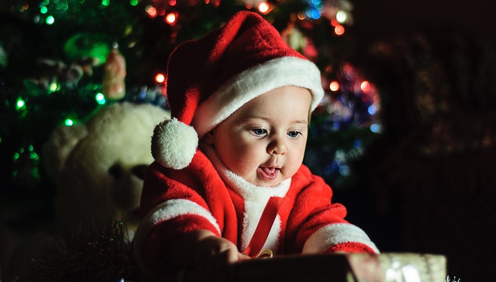 Kerstkaarten 2018: baby in kerstpakje onder de kerstboom