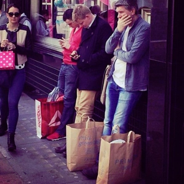 Mannen wachten op vrouw terwijl zij shopt