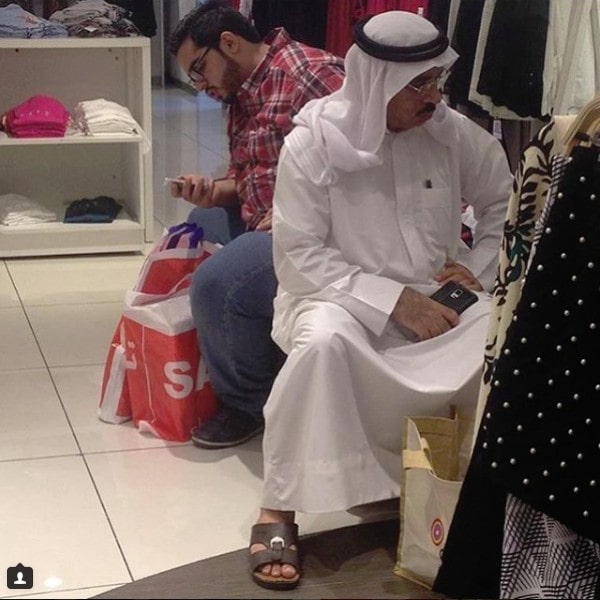 Mannen wachten op vrouw terwijl zij shopt