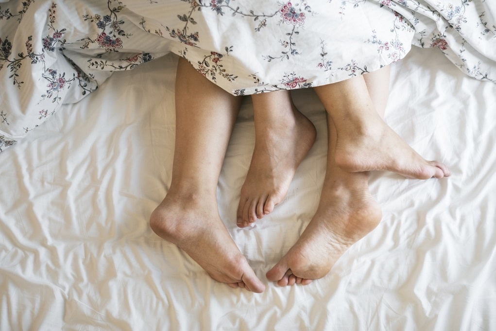 Voeten van man en vrouw in bed