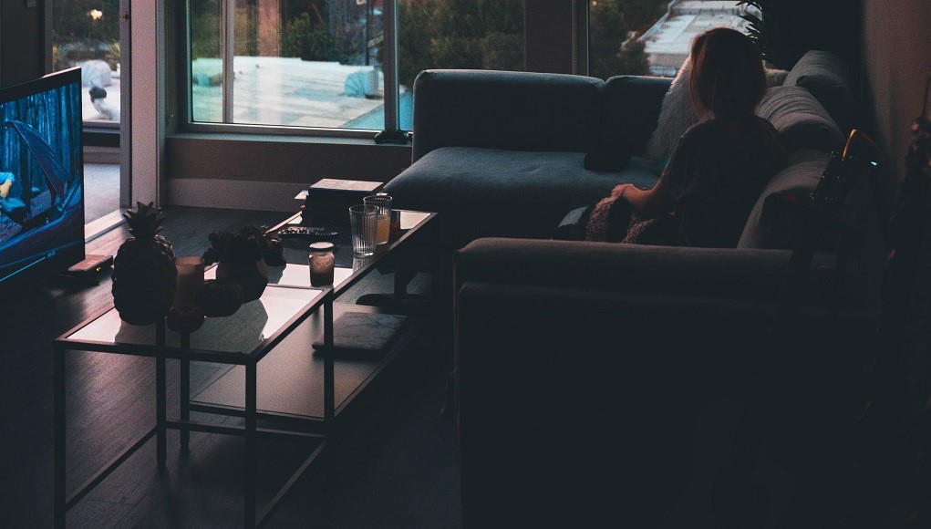 Vrouw zit op de bank en kijkt tv-series