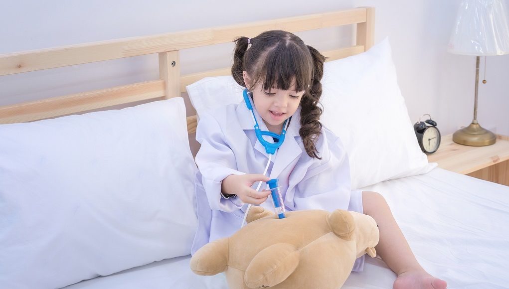 Klein meisje geeft haar teddybeer een vaccinatie