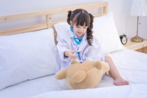 Klein meisje geeft haar teddybeer een vaccinatie