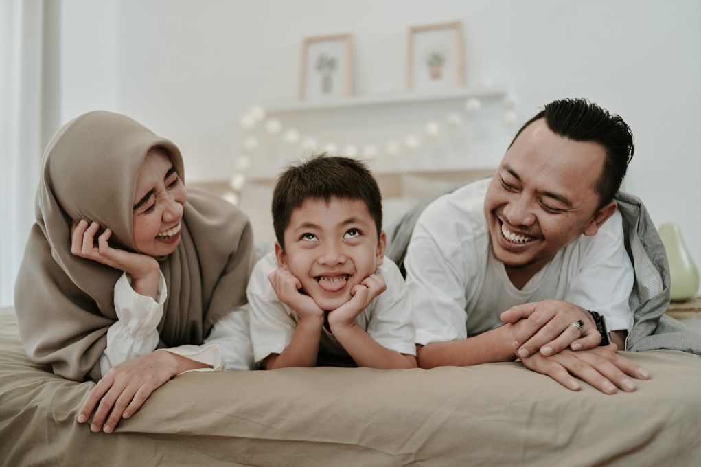 Blij gezin ligt samen op bed en praat over de juiste zorgverzekering voor je gezin