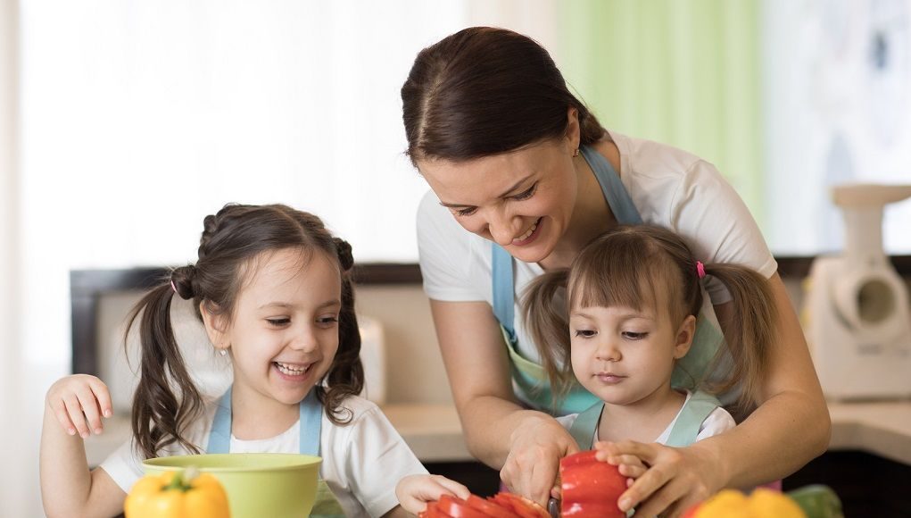 Moeder helpt haar kinderen met gezond eten door samen te koken