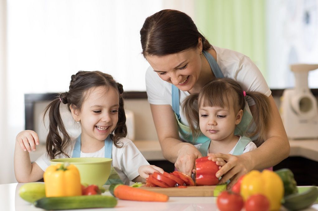Moeder helpt haar kinderen met gezond eten door samen te koken