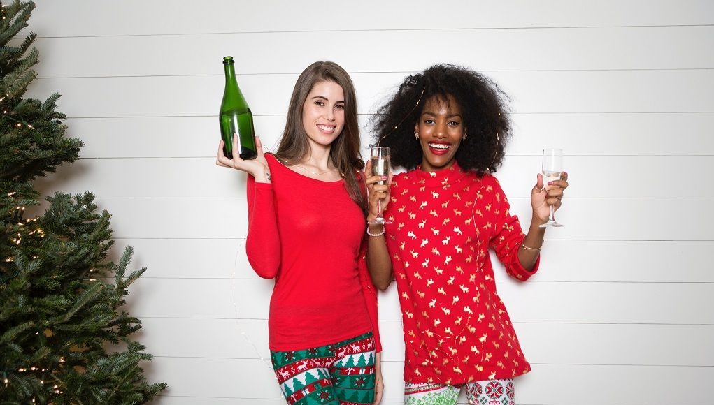 Twee vrouwen in kerstkleding proosten met champagne