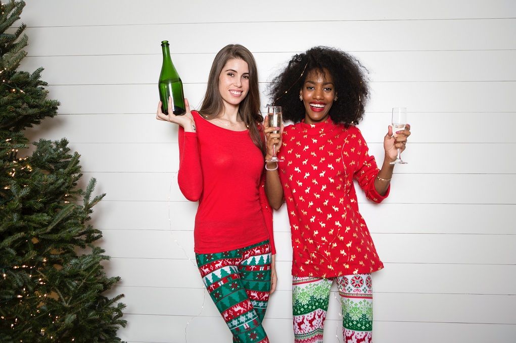 Twee vrouwen in kerstkleding proosten met champagne