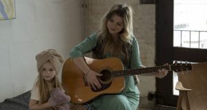 Zangeres Jennifer Ewbank met haar dochter en haar gitaar