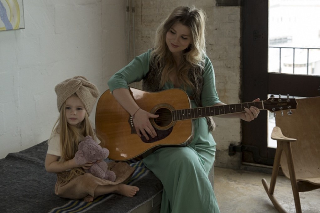 Zangeres Jennifer Ewbank met haar dochter en haar gitaar
