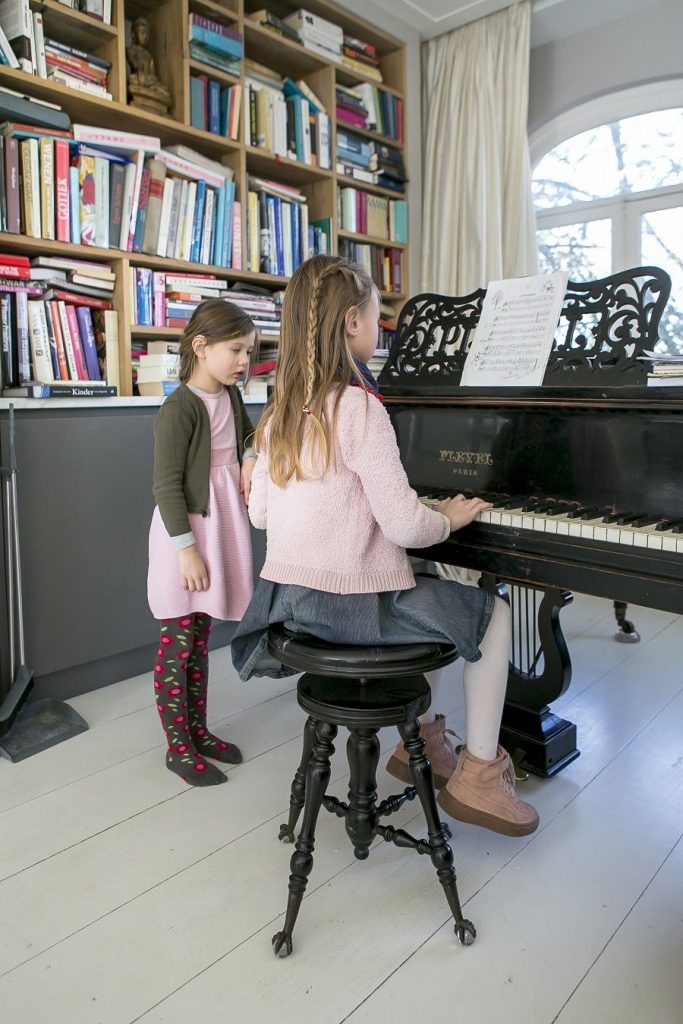 Kleine meisjes achter een vleugel in hun woonkamer