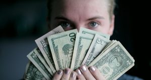 Vrouw houdt bankbiljetten voor haar gezicht