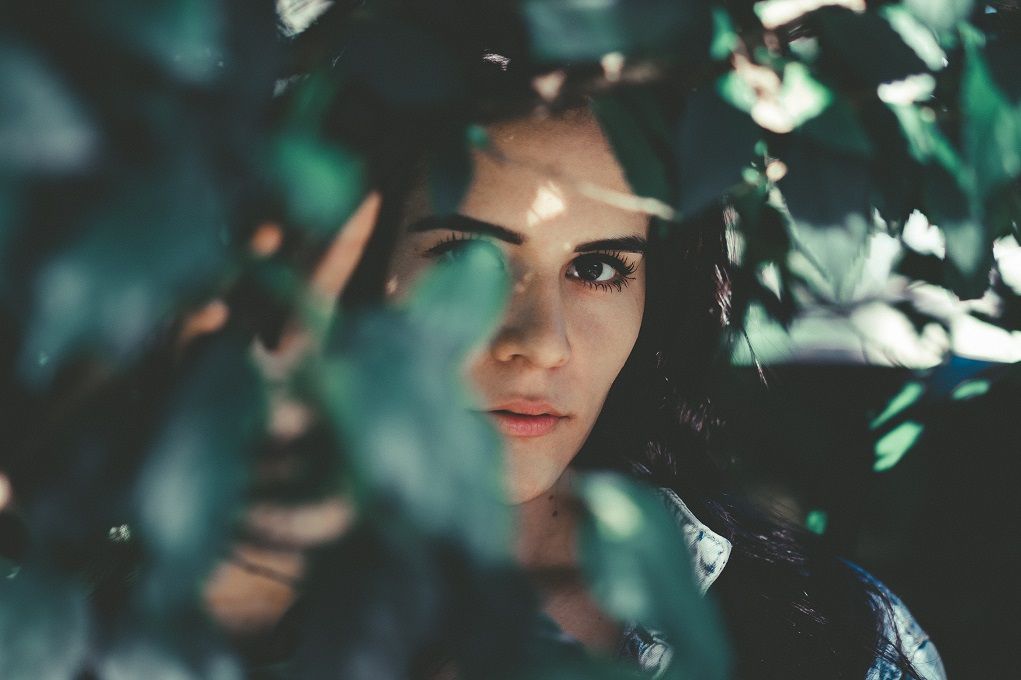 Vrouw verstopt zich achter bladeren