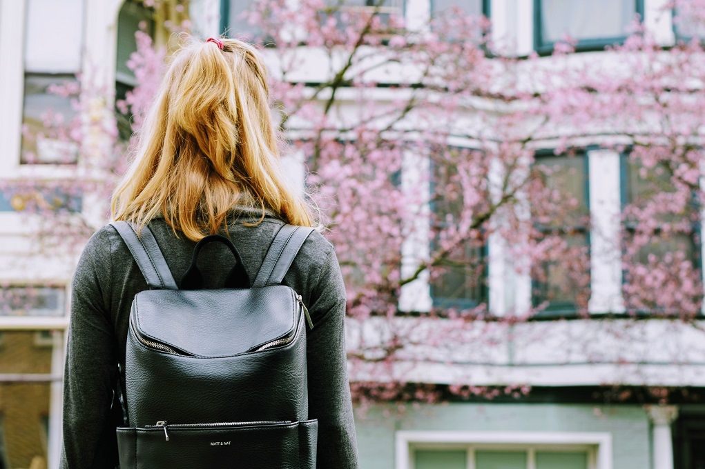 Vrouw met rugzak kijkt naar bloesemboom