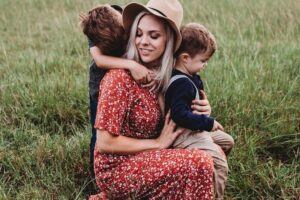 Moeder knuffelt haar twee zoontjes in een weiland