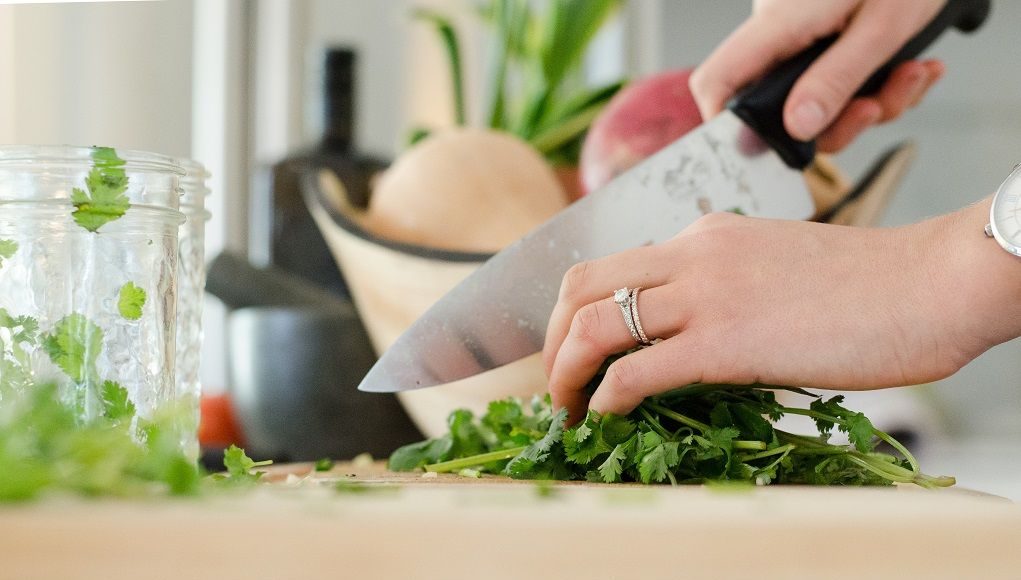 Vrouw snijdt groente met koksmes