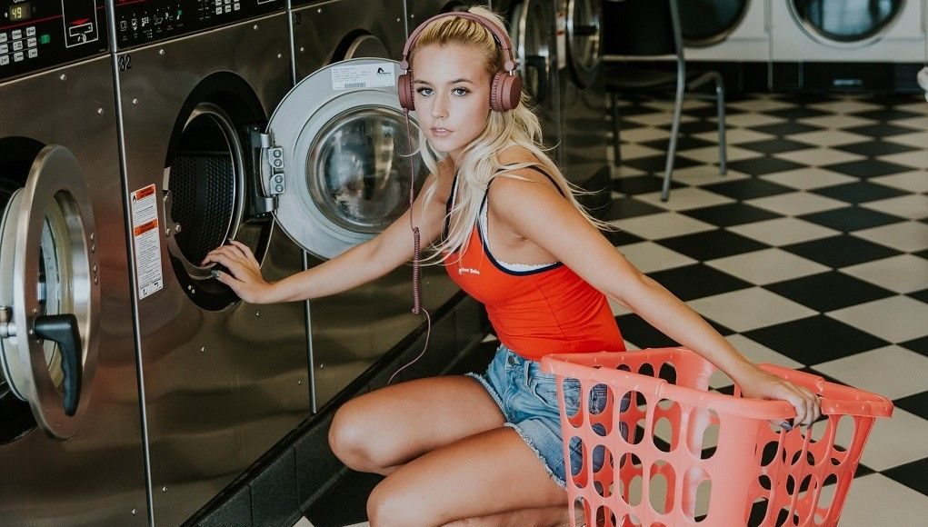 Vrouw bij wasserette hurkt voor wasmachine